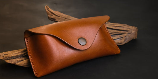 a brown leather eyeglasses case on a desk