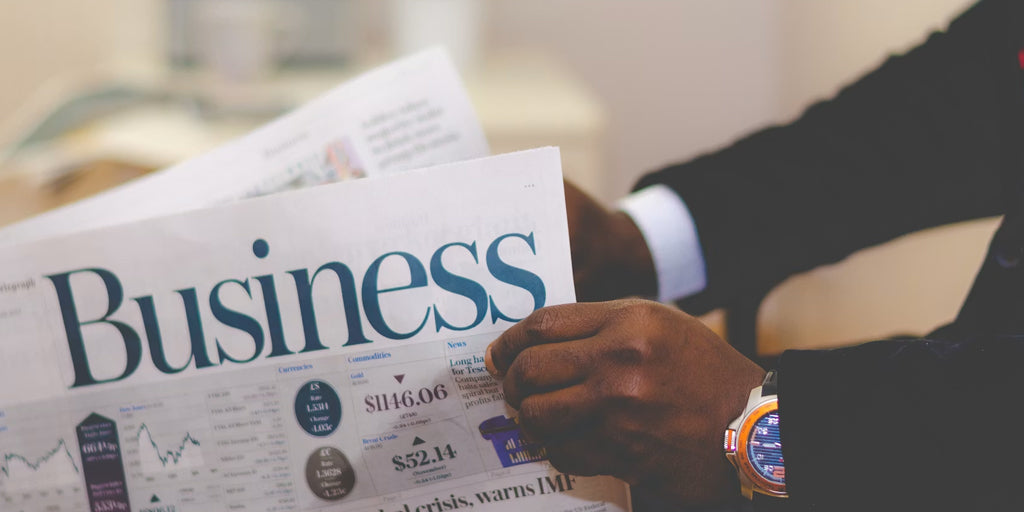 a man wearing a luxury watch reading a business news paper