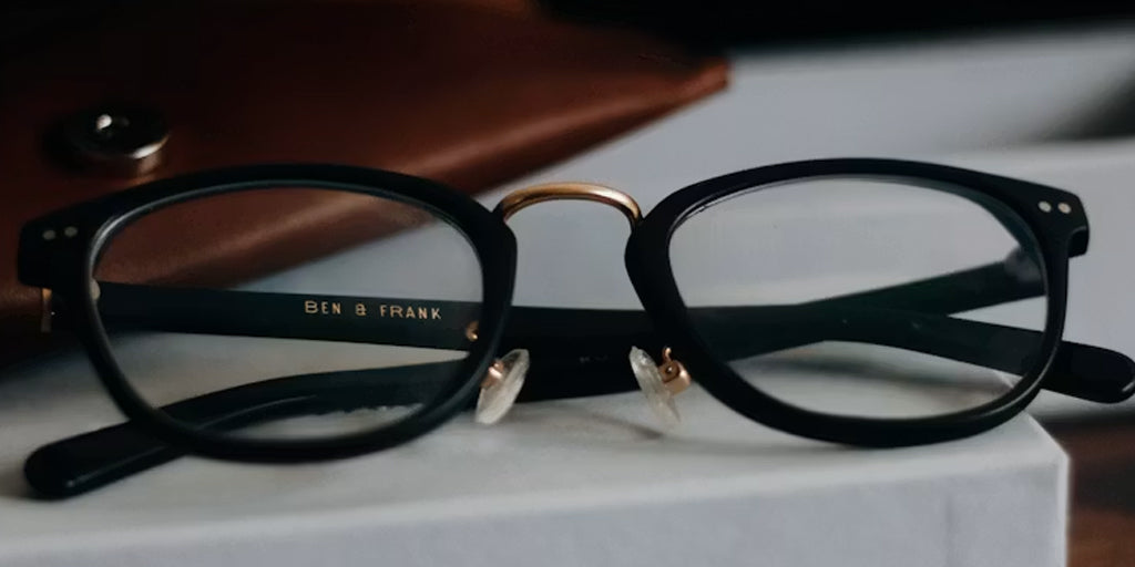 a pair of glasses with a leather glasses case behind it