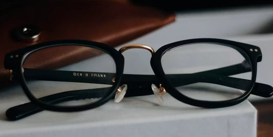 a pair of glasses with a leather glasses case behind it