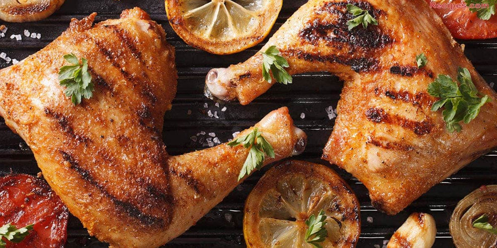 well grilled chicken thighs on a grill with some lemon slices