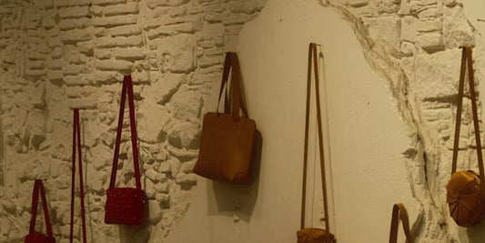 several leather crossbags hung on the wall