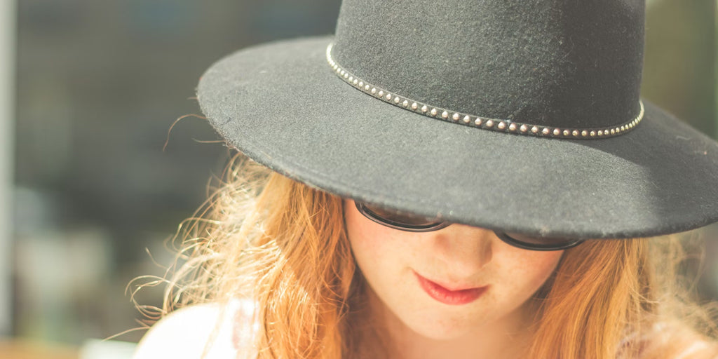 a lady wear sunglasses and a hat