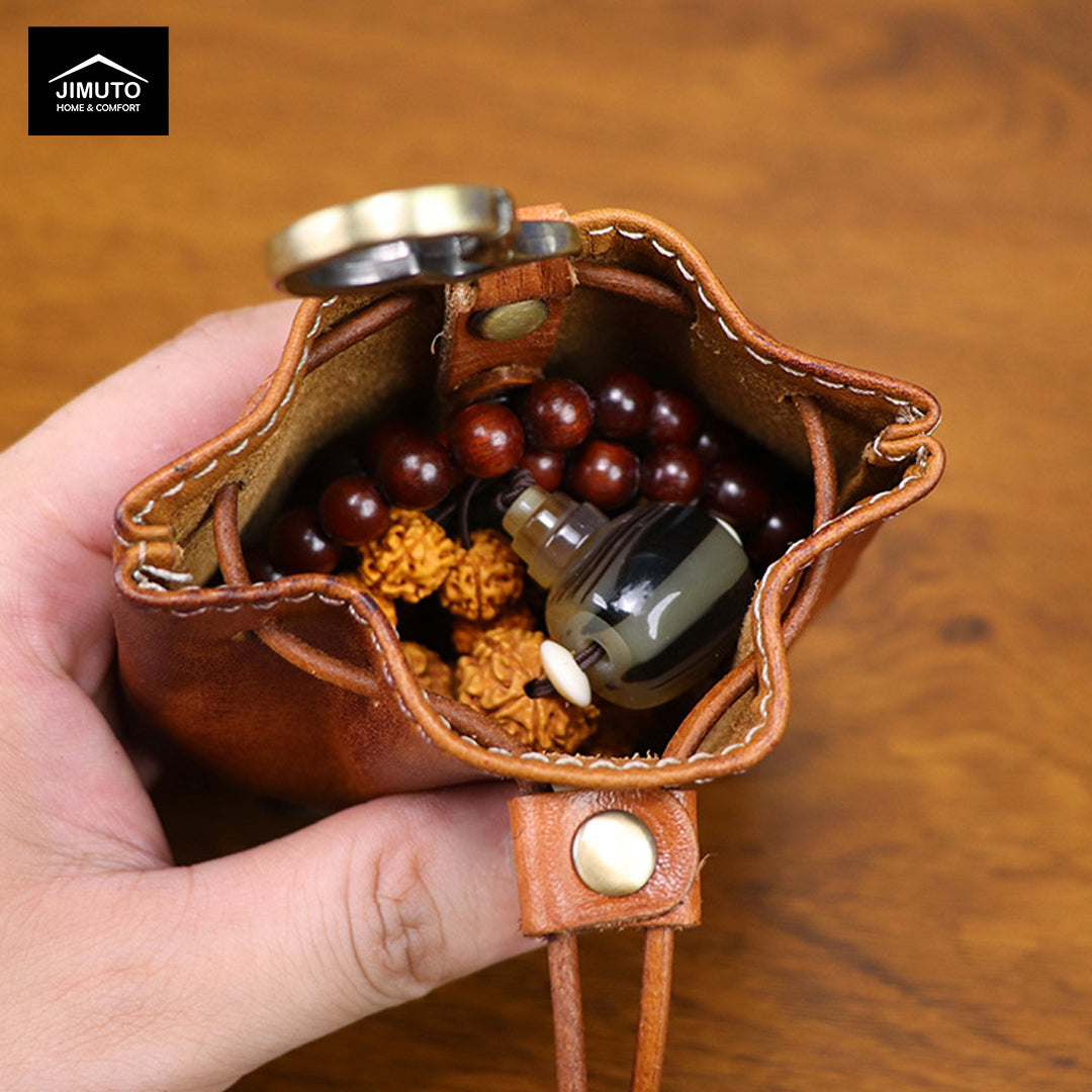 Brown leather pouch with keychain holding berries and a bottle, on a wooden surface.