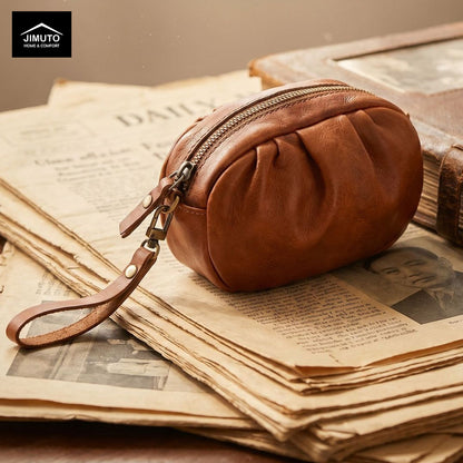 Brown leather pouch with a strap on top of an old newspaper, with 'JIMUTO' brand visible.