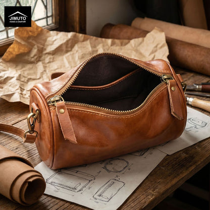 Brown leather cosmetic and storage bag on a wooden table with architectural drawings and JIMUTO branding.