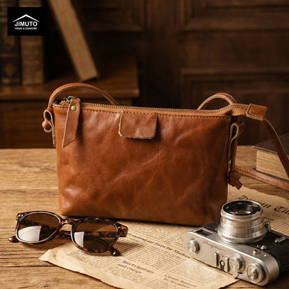 Brown leather crossbody bag on a a desk with 'JIMUTO' showing