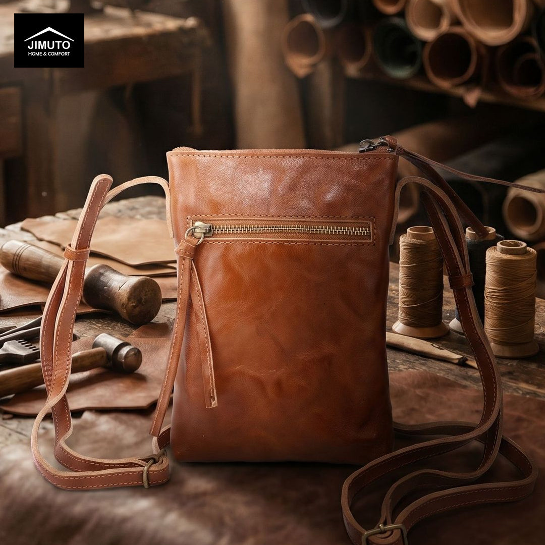Brown leather crossbody bag on a wooden surface with leather tools and materials.