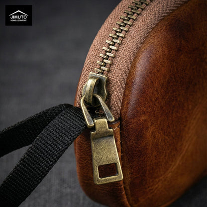 Close-up of a brown leather coin purse with a brass zipper on a dark background