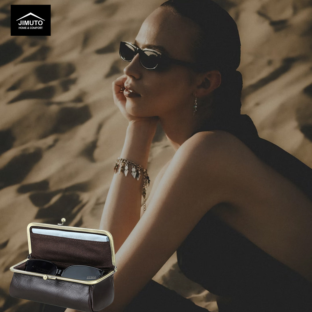 Woman sitting in a desert setting with a black leather eyeware box and clutch and sunglasses, JIMUTO logo visible.