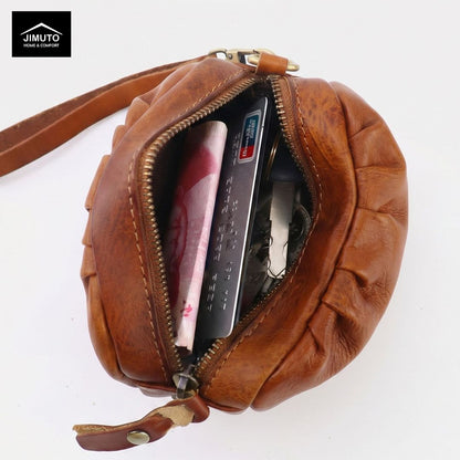 Brown leather pouch with zipper, containing money and a card, on a white background.