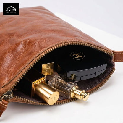 Brown leather clutch with gold and black perfume bottles on a white background