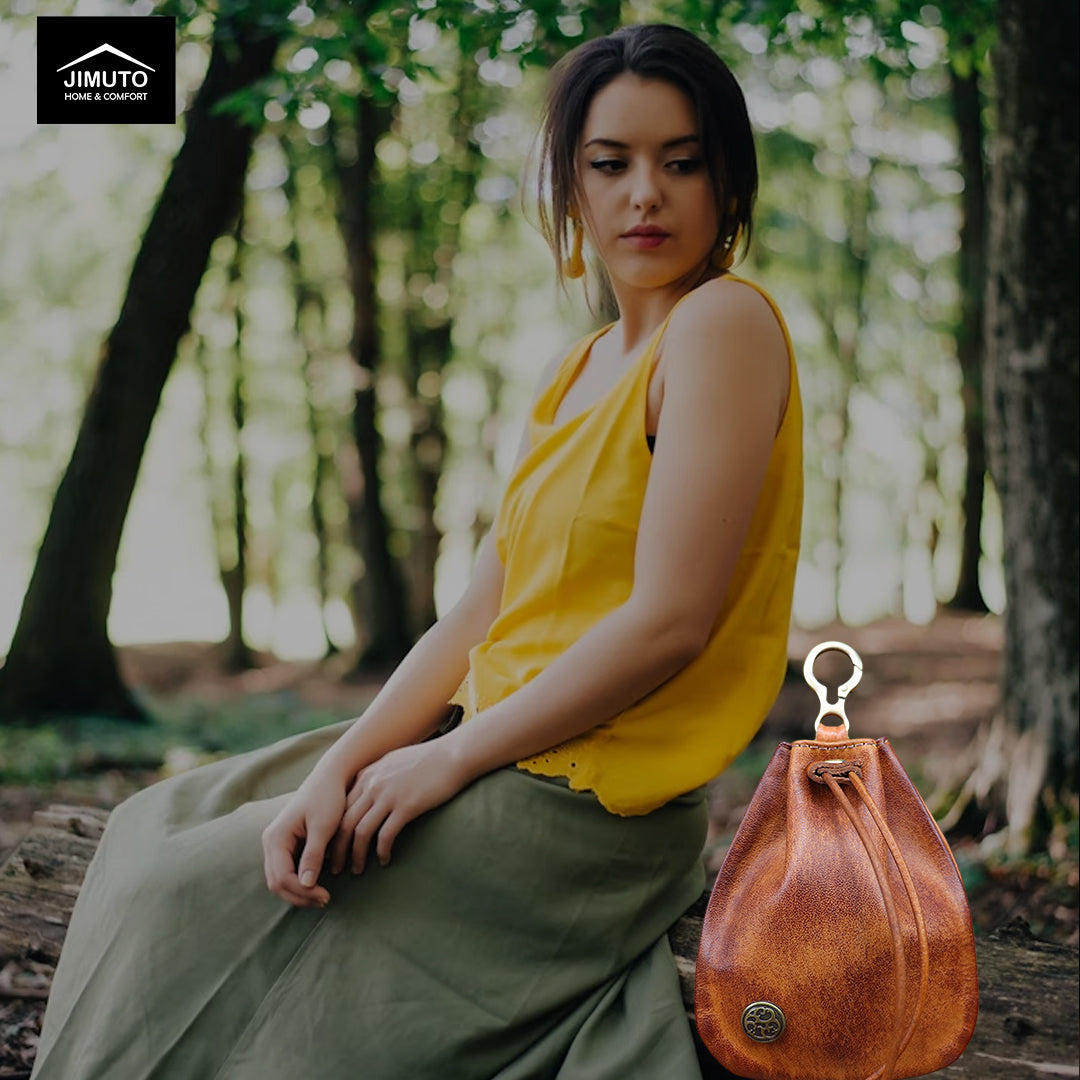 Woman in yellow top and green pants sitting outdoors with a brown leather bag beside her.