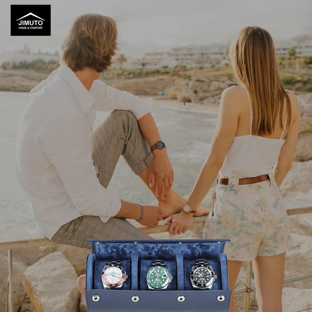 Two people sitting by a beach with a blue saffiano watch box containing three watches in the foreground.
