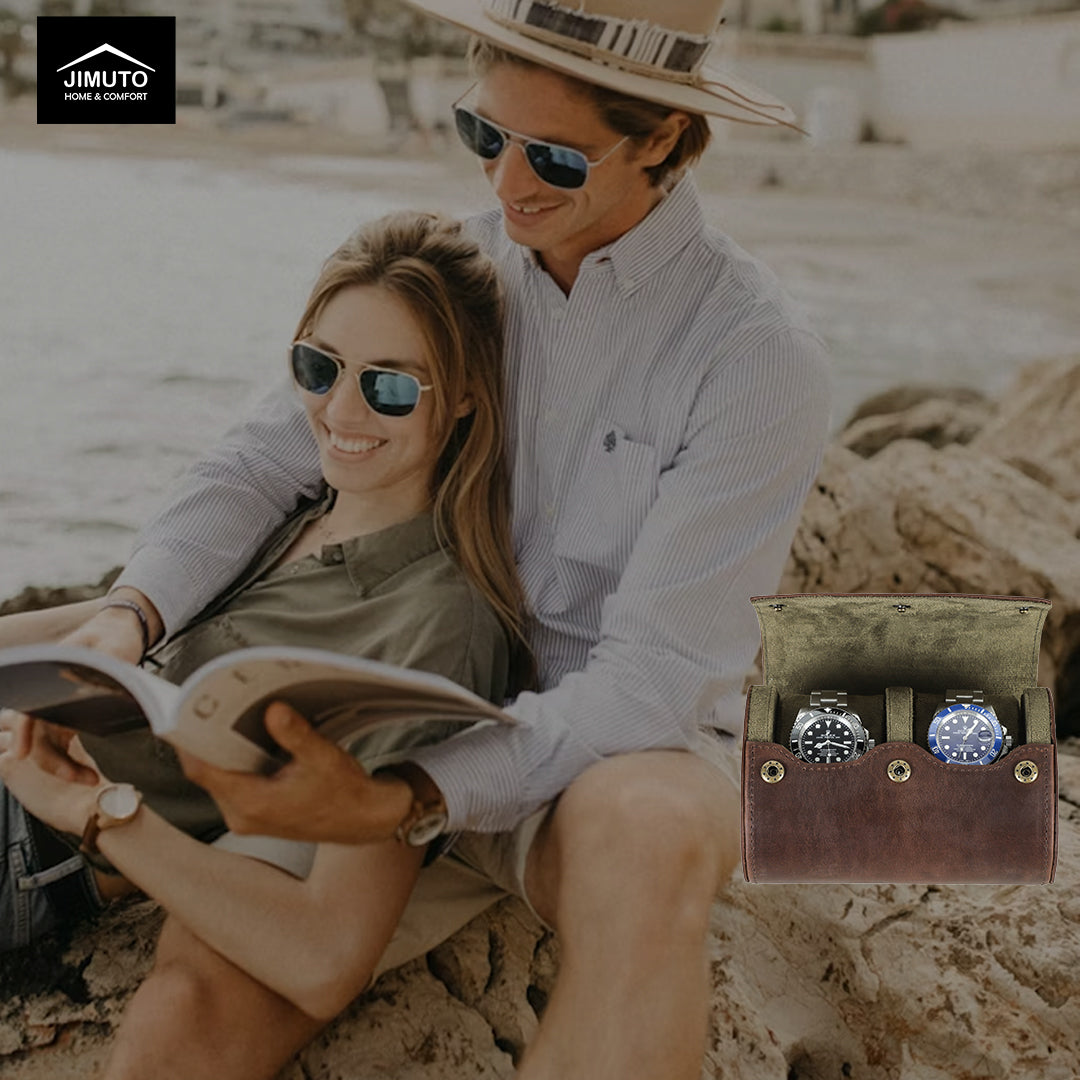 Couple sitting on a beach reading a book with a leather watch display case featuring two watches.