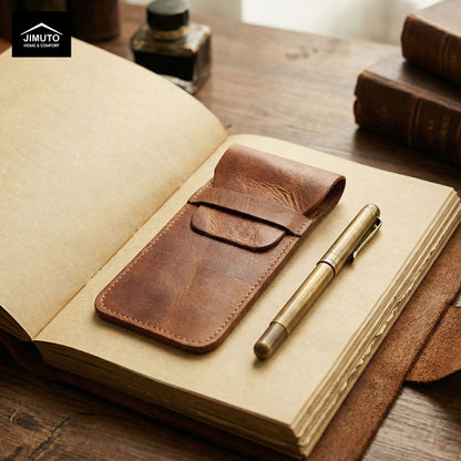 Brown leather pen pouch and pen on an open notebook with a wooden surface and books in the background.