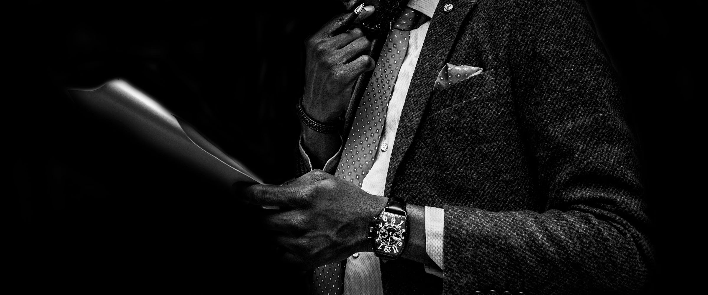 Man adjusting his tie with a watch on his wrist, black and white photo