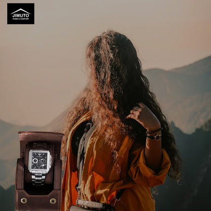 Person with long hair and a backpack standing on a mountain with a watch in the foreground.