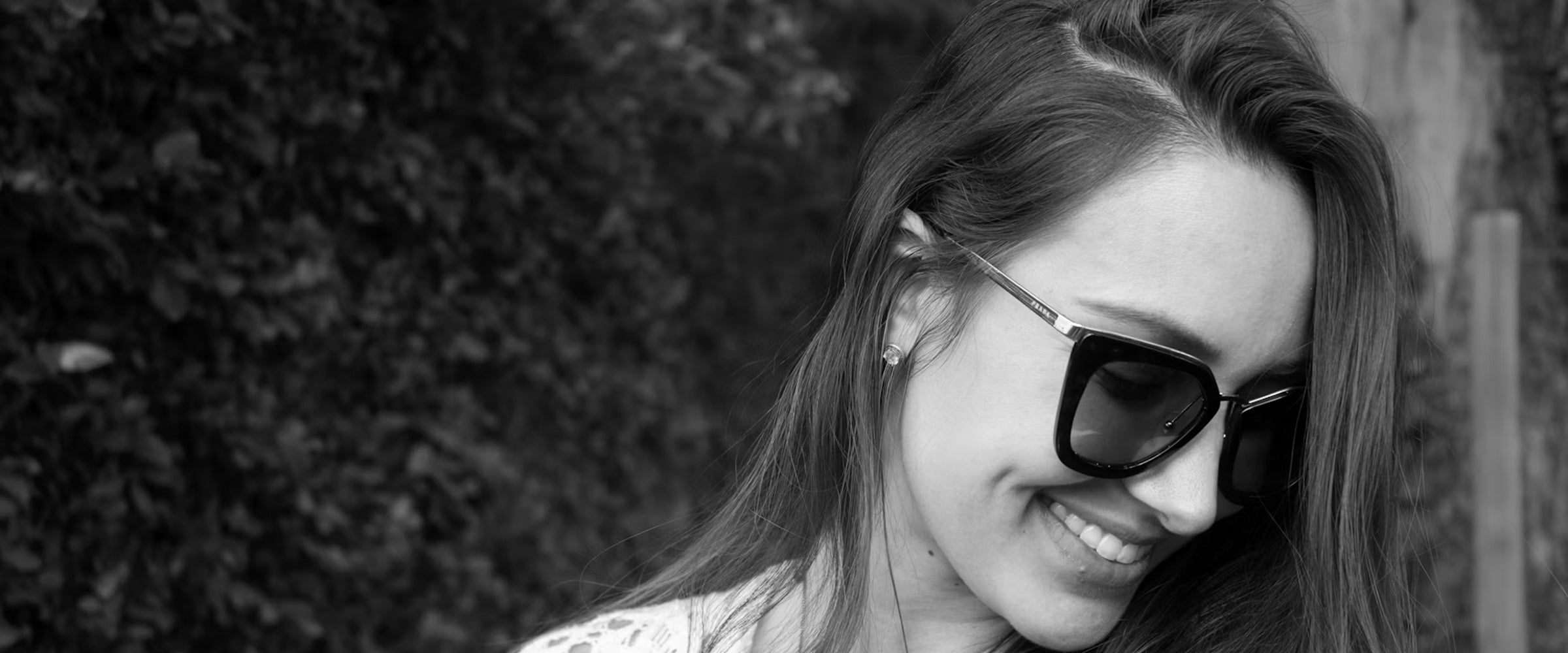 Black and white photo of a woman wearing sunglasses with a blurred background