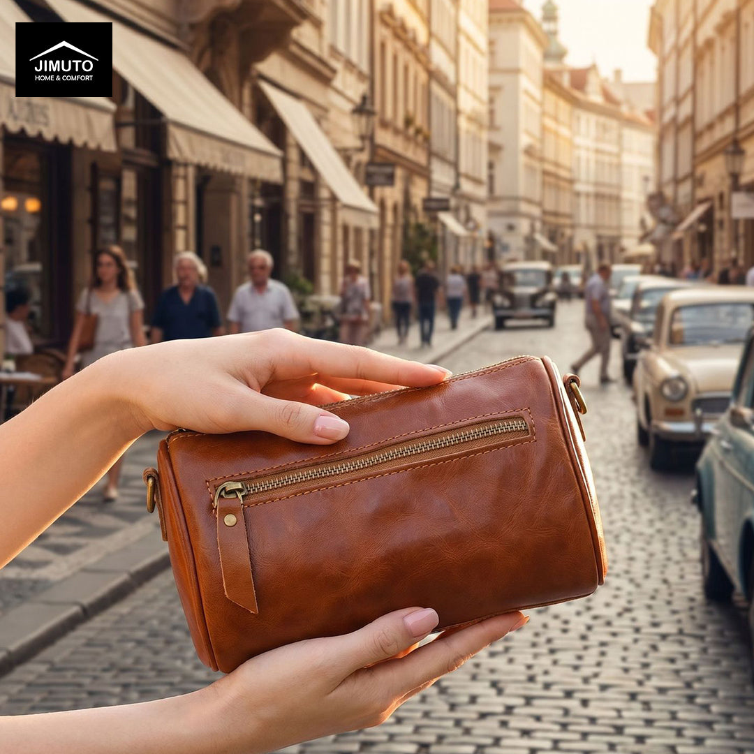 Brown leather cosmetic and storage  bag held by a hand on a city street with people and vintage cars in the background.