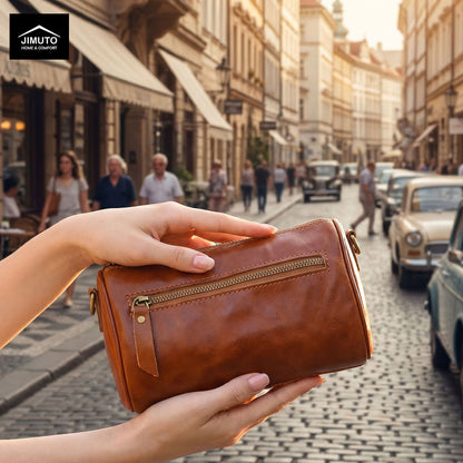 Brown leather cosmetic and storage  bag held by a hand on a city street with people and vintage cars in the background.