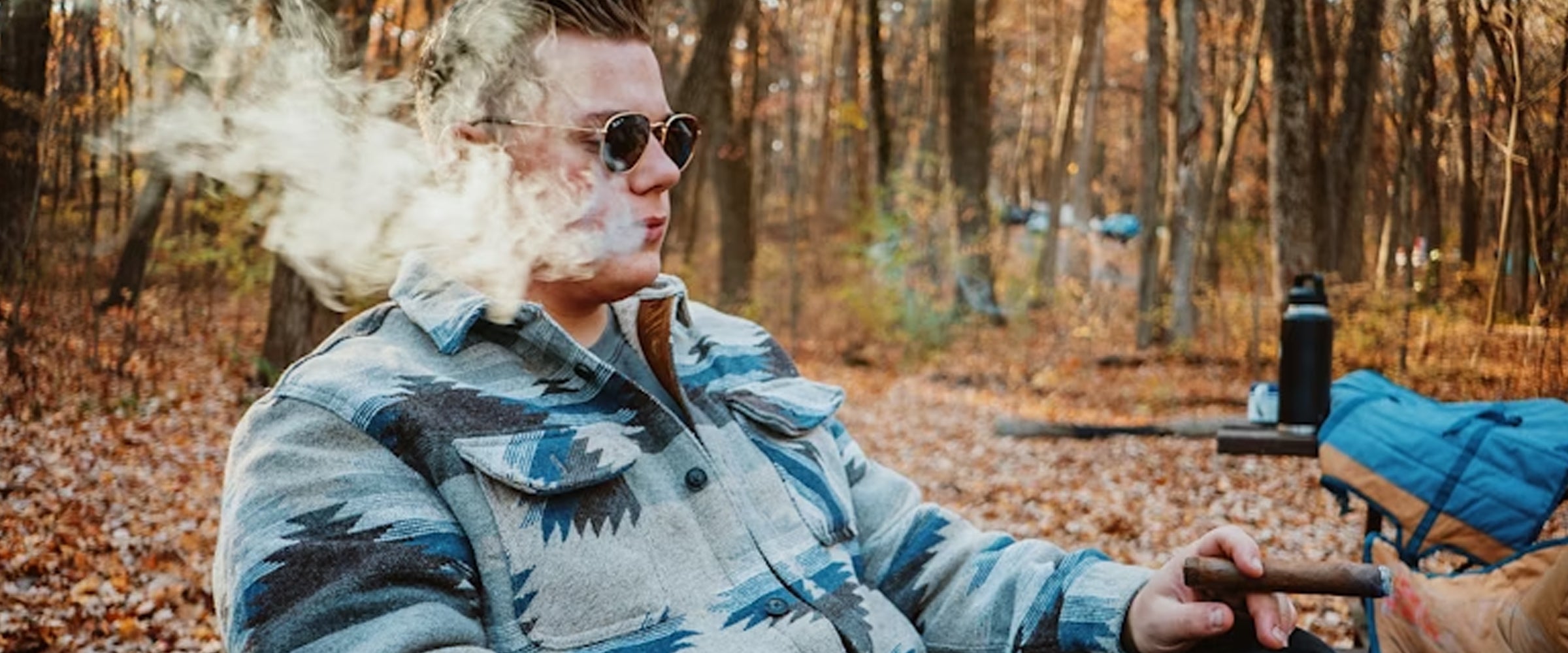Man smoking a cigar in a forest setting