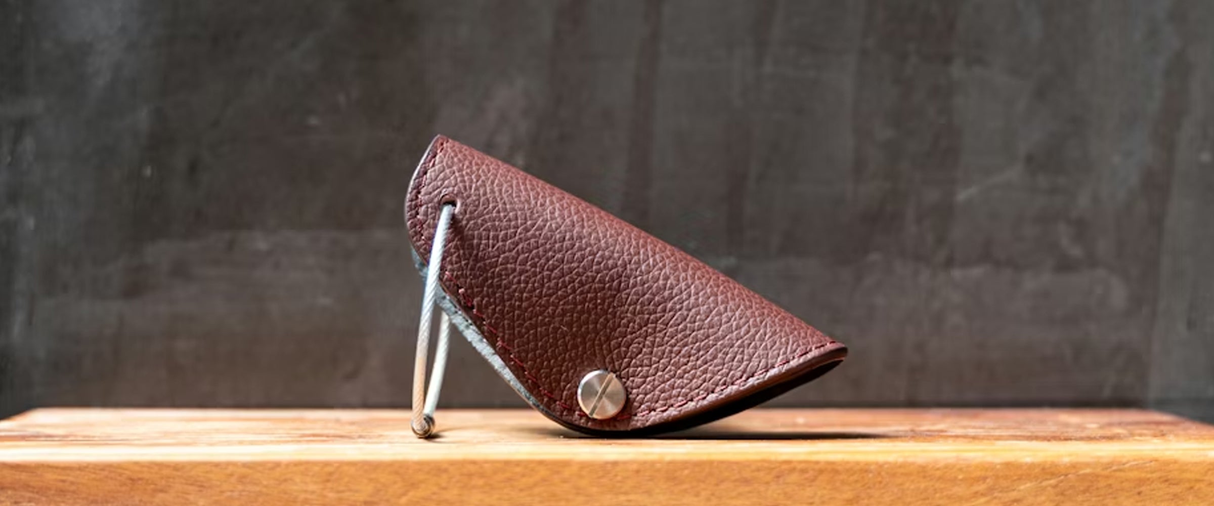 Brown leather case with metal stand on a wooden surface