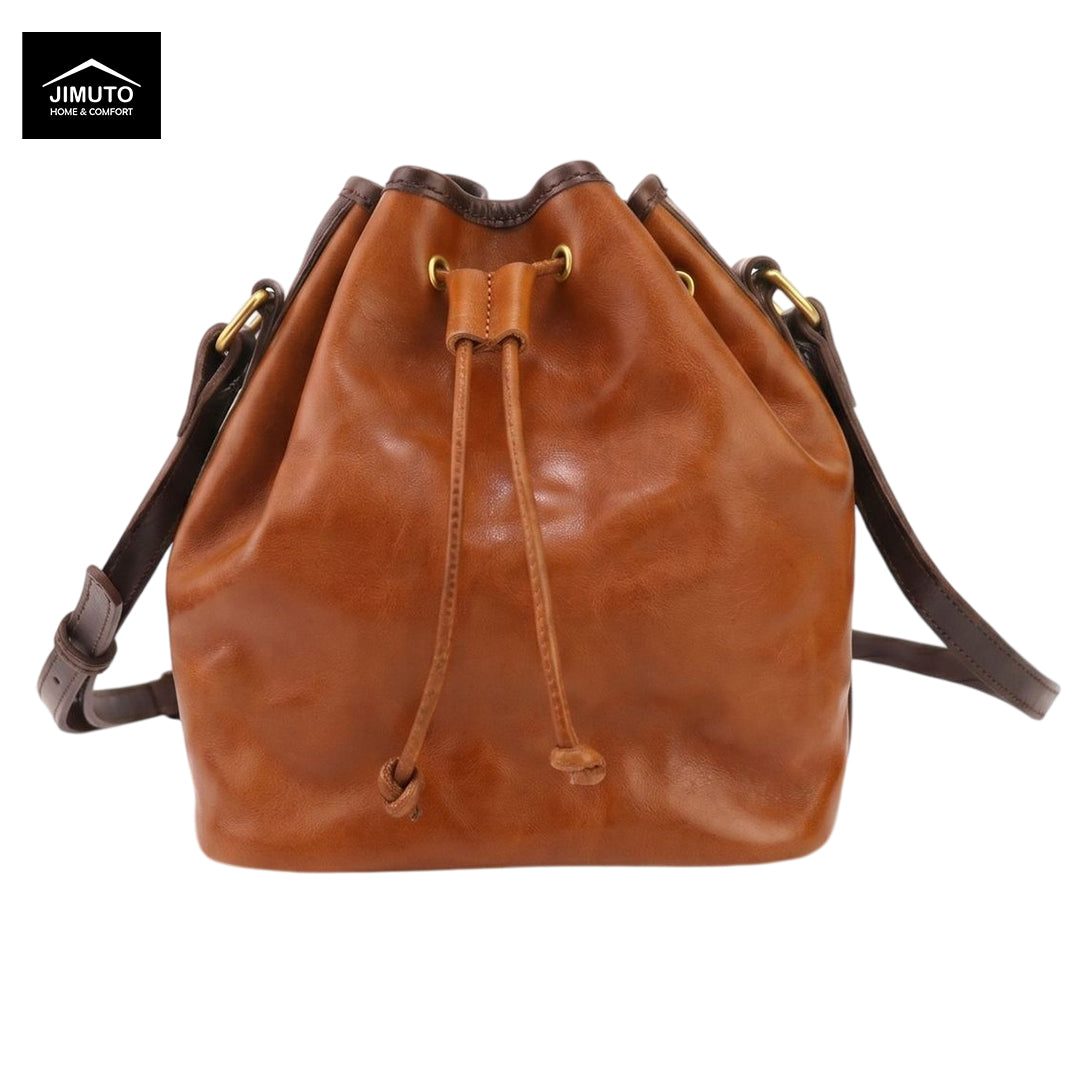 A brown top-grain leather bucket bag with a drawstring closure and a shoulder strap, shown on a white background with a Jimuto logo in the top-left corner.