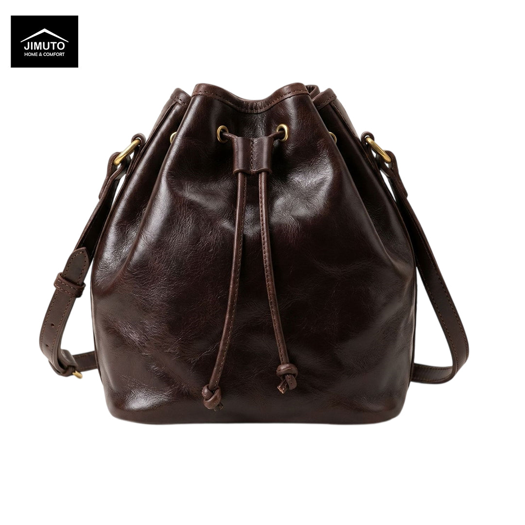 A dark brown top-grain leather bucket bag with a drawstring closure and adjustable shoulder strap, shown on a plain white background with a Jimuto logo in the top-left corner.