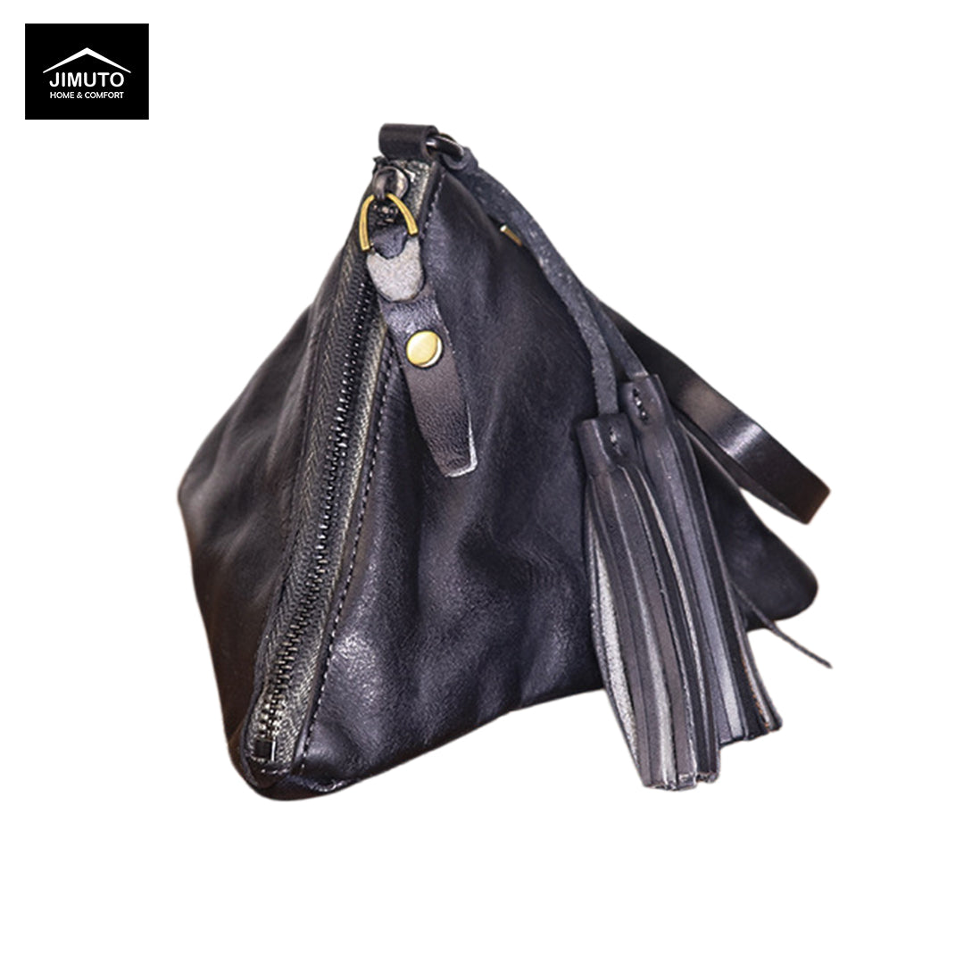 A black full-grain leather clutch with a slouchy triangular shape, featuring a top zipper, a hanging tassel detail, and a gold snap button. The brand logo 'JIMUTO' is visible in the top-left corner.