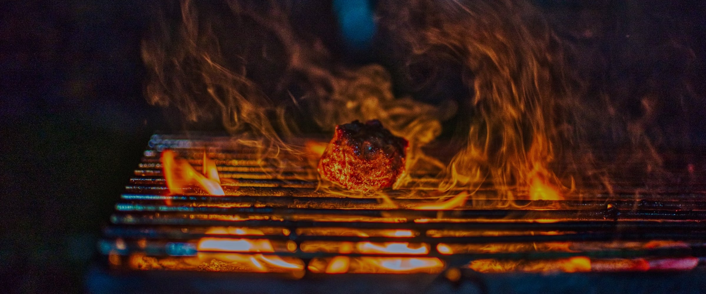 Meat on a grill with flames and smoke