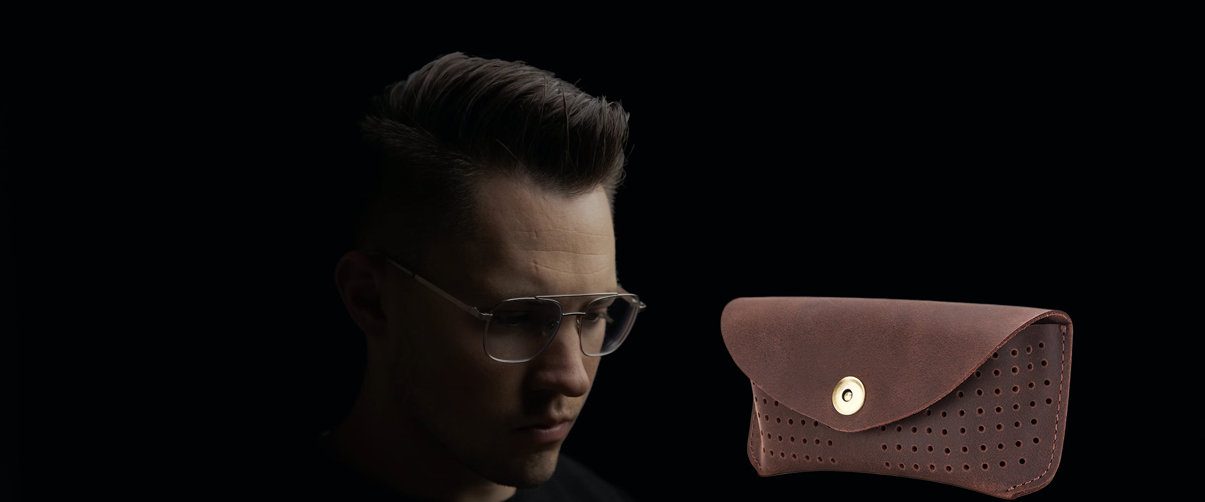 Man wearing sunglasses with a brown leather eyeglasses case on a black background