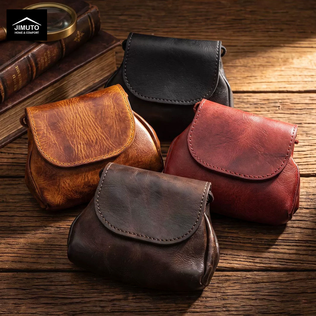 Four small leather pouches or clutches in different colors—black, tan, reddish brown, and dark brown—are arranged on a rustic wooden surface. A vintage book and magnifying glass sit in the background, and a Jimuto logo appears in the top-left corner.