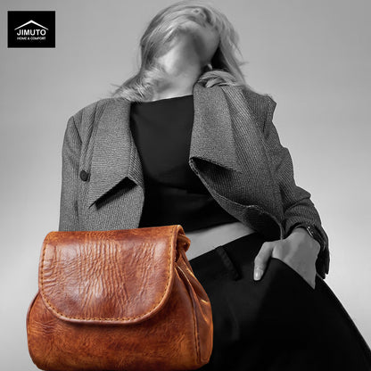 A model wearing a gray blazer and black top carries a brown leather pouch. The image is desaturated with a black-and-white effect on the model, while the bag retains its natural color.