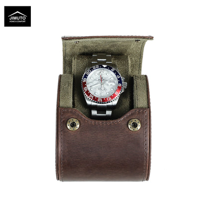A wristwatch with a silver metal bracelet and a red, white, and blue bezel sits inside an open brown leather watch case with an olive green interior. The Jimuto brand logo is visible in the top-left corner.