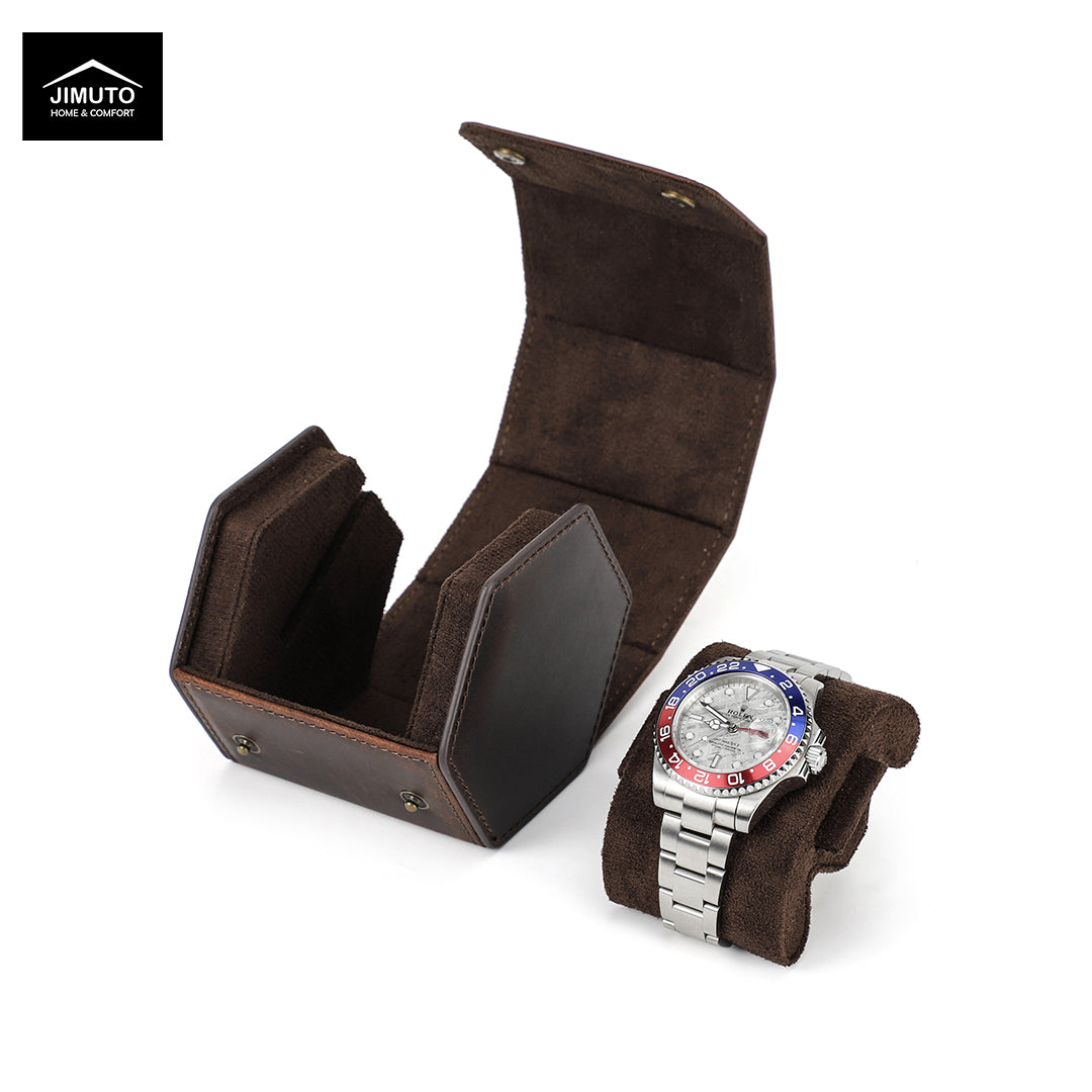 A dark brown hexagonal leather watch box by Jimuto, featuring an open fold-out storage case and a matching cushion holding a silver metal watch with a red and blue bezel, on a white background.