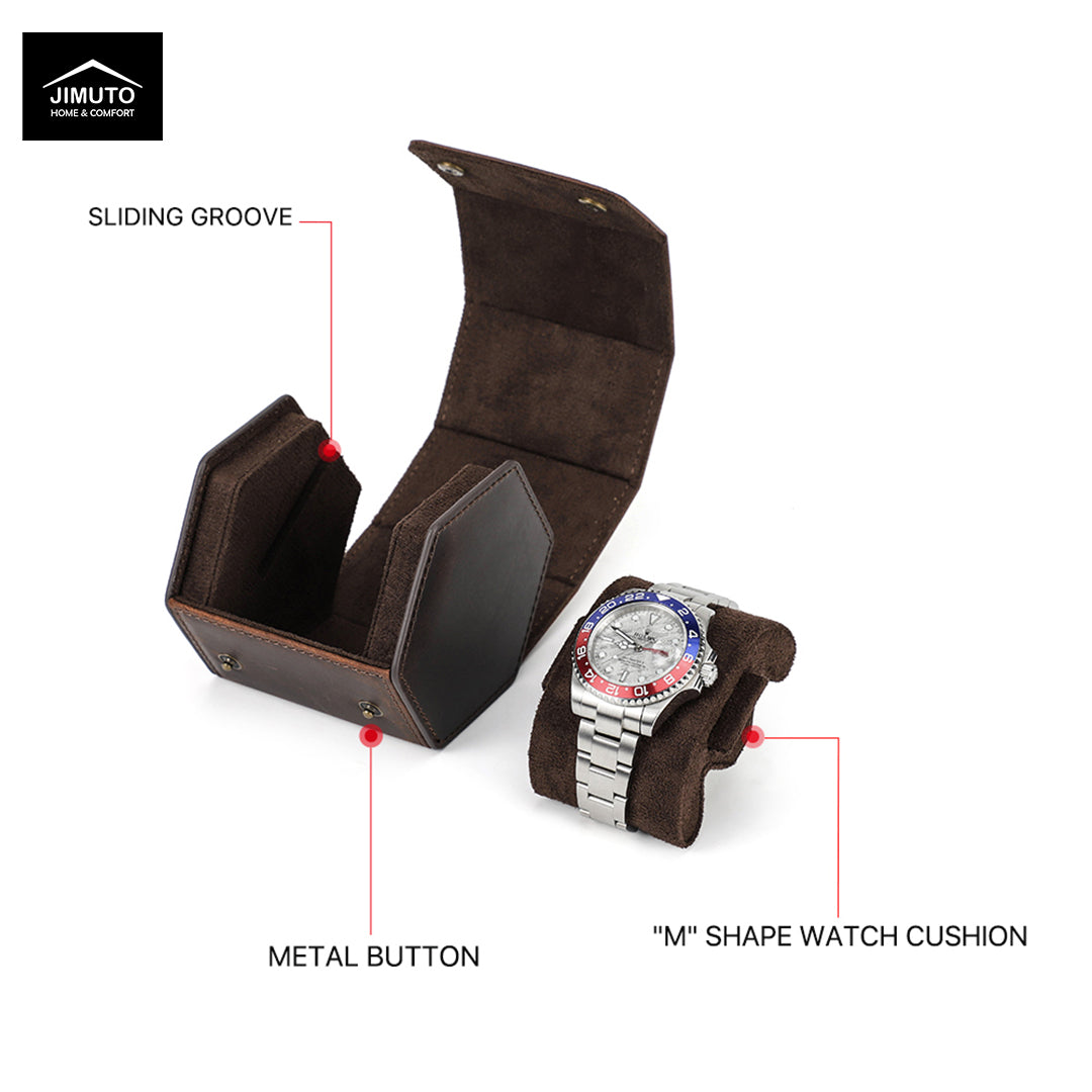 A dark brown hexagonal leather watch case and matching watch cushion set shown on a white background with callout labels. The open box has a sliding groove and metal button, and the cushion holds a silver wristwatch with a blue and red bezel.
