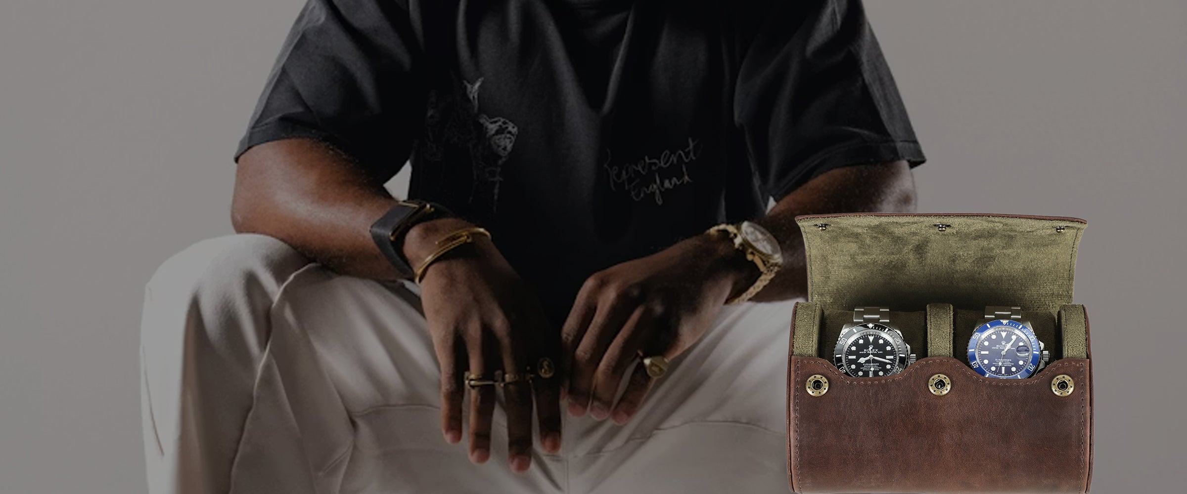 Person wearing jewelry with a focus on watches in a display leather watch case.