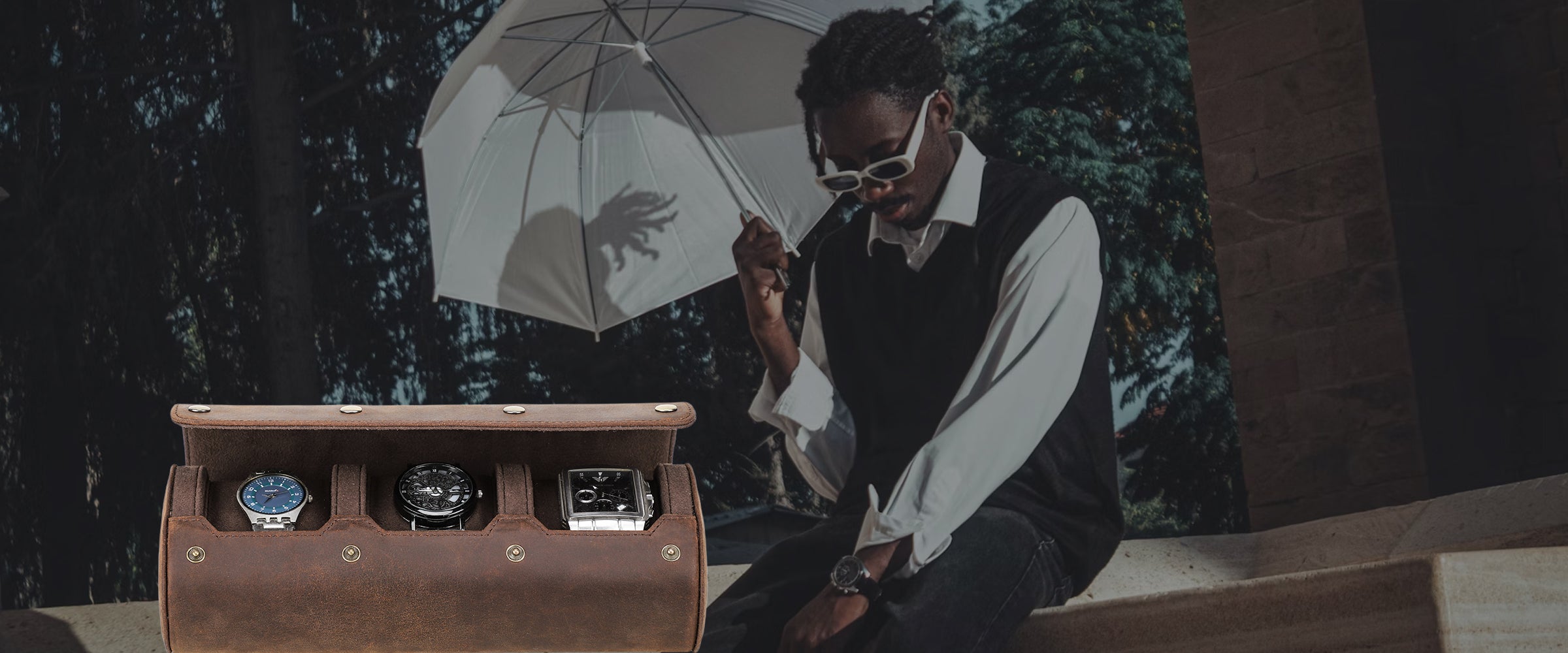 Man holding an umbrella, next to a leather watch case.